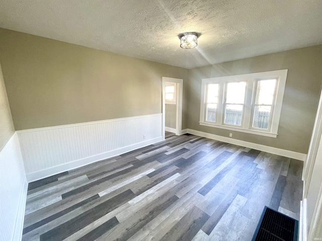 unfurnished room featuring a textured ceiling and dark wood-type flooring