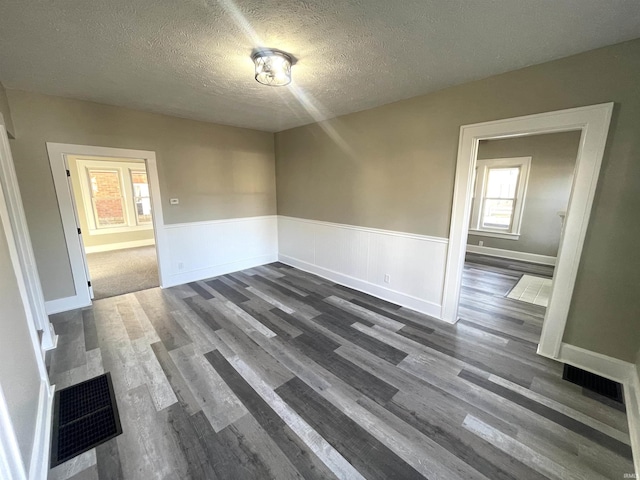 spare room featuring a textured ceiling and dark wood-type flooring