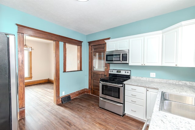 kitchen featuring light stone countertops, sink, wood-type flooring, white cabinets, and appliances with stainless steel finishes