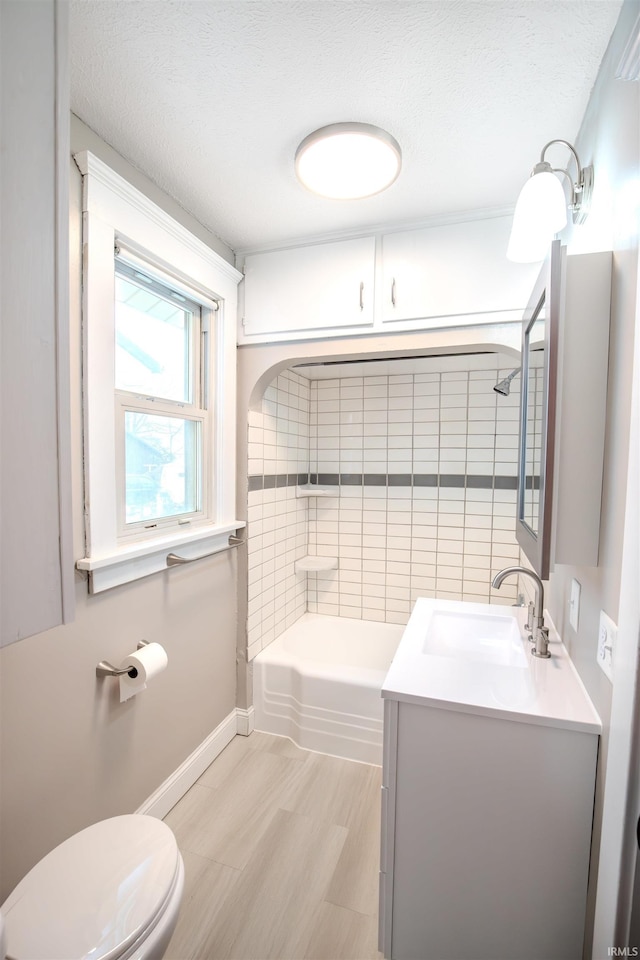 full bathroom with vanity, tiled shower / bath, toilet, a textured ceiling, and wood-type flooring