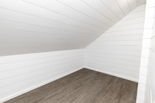 bonus room with lofted ceiling, wood walls, and dark hardwood / wood-style floors