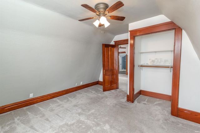 unfurnished bedroom with ceiling fan, a closet, light carpet, and vaulted ceiling