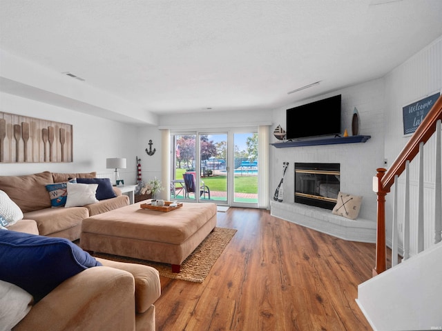 living room with a brick fireplace and hardwood / wood-style flooring