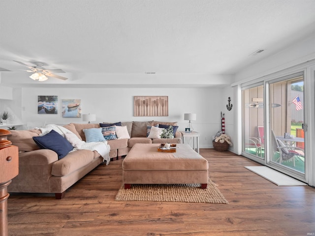 living room with a textured ceiling, ceiling fan, and dark wood-type flooring