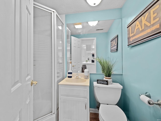 bathroom featuring a textured ceiling, vanity, toilet, and walk in shower