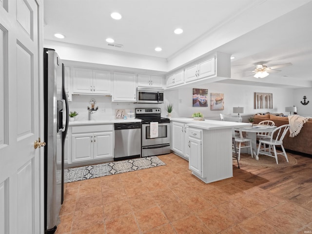 kitchen with ceiling fan, kitchen peninsula, appliances with stainless steel finishes, white cabinets, and light wood-type flooring