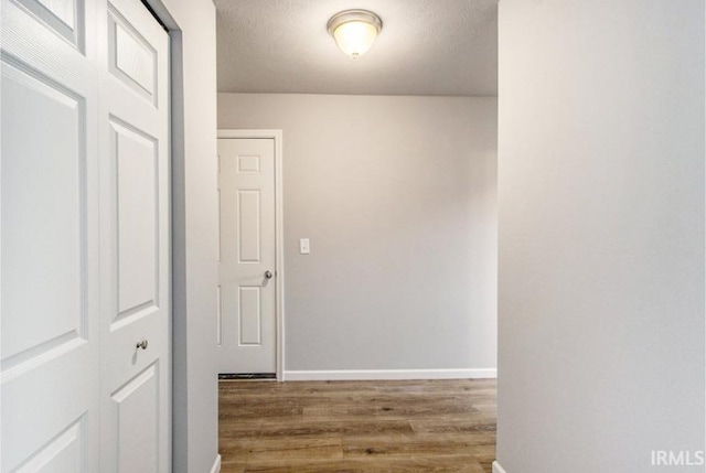 hall with wood-type flooring and a textured ceiling