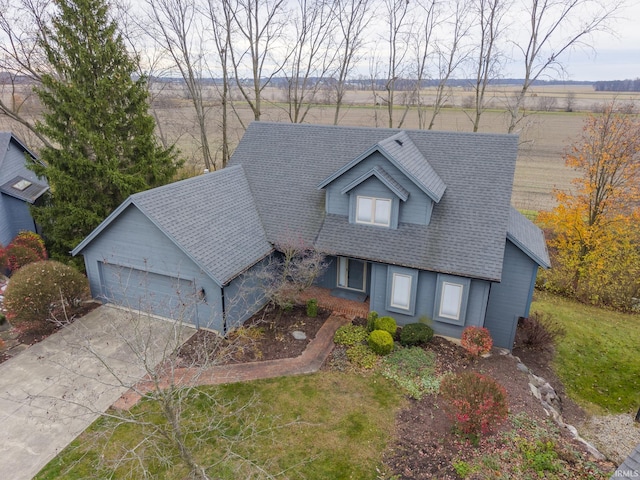 cape cod home with a rural view, a garage, and a front lawn