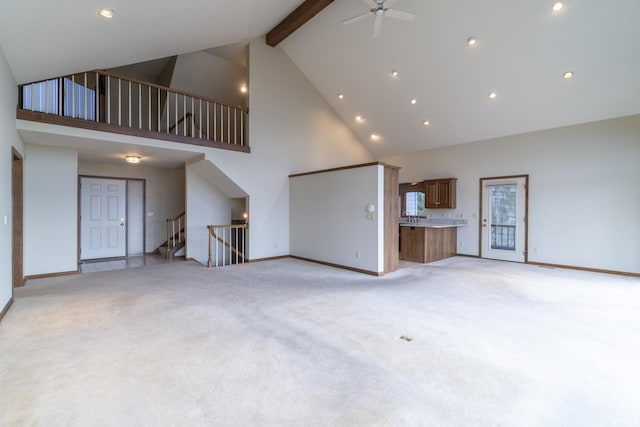 unfurnished living room with light carpet, beam ceiling, high vaulted ceiling, and ceiling fan