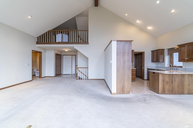 kitchen with beamed ceiling, light colored carpet, kitchen peninsula, and high vaulted ceiling