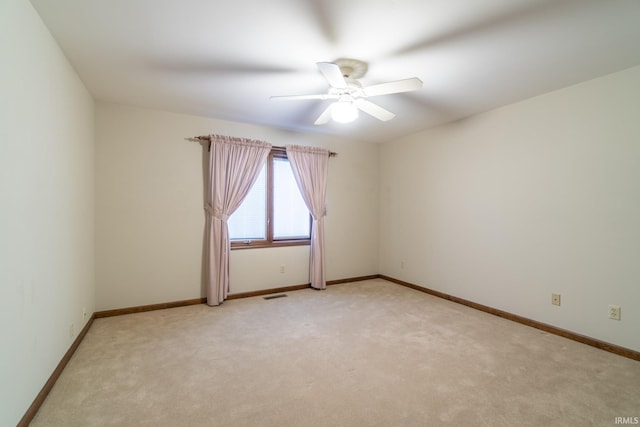 empty room featuring ceiling fan and light colored carpet