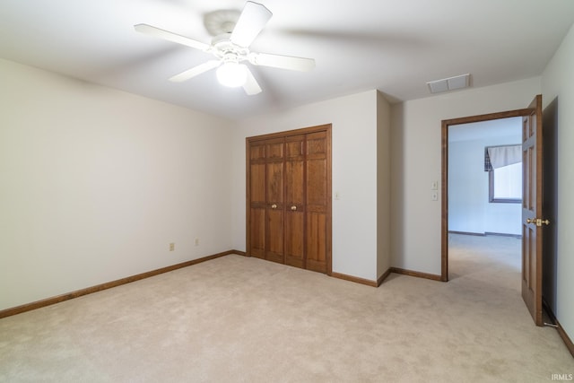 unfurnished bedroom with ceiling fan, light colored carpet, and a closet