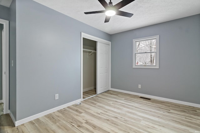 unfurnished bedroom featuring ceiling fan, a closet, a textured ceiling, and light hardwood / wood-style flooring