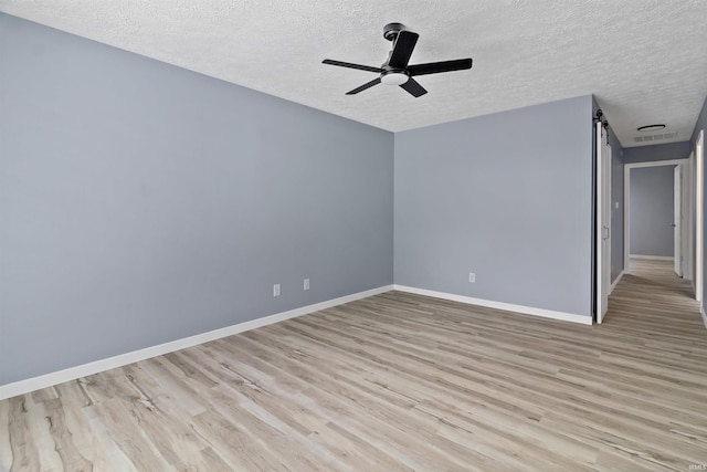 empty room with ceiling fan, light hardwood / wood-style flooring, and a textured ceiling