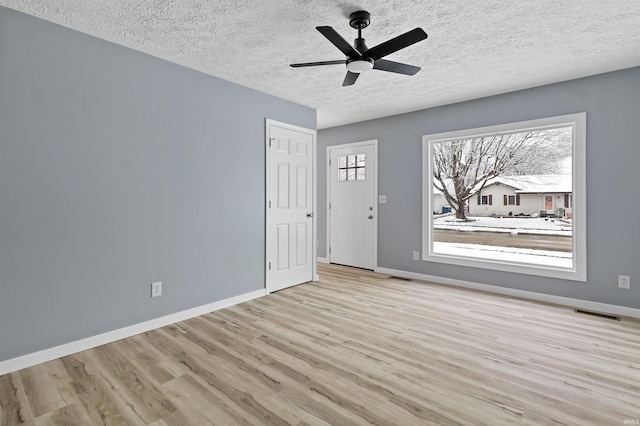 spare room with a textured ceiling, light hardwood / wood-style floors, and ceiling fan