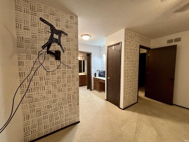 corridor with a textured ceiling and light colored carpet