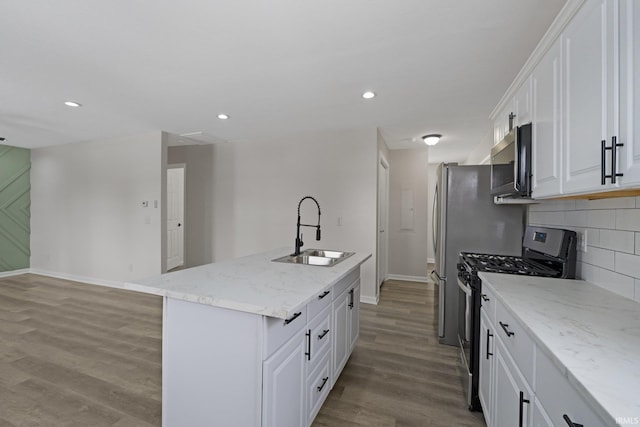 kitchen featuring appliances with stainless steel finishes, light wood-type flooring, a kitchen island with sink, sink, and white cabinets