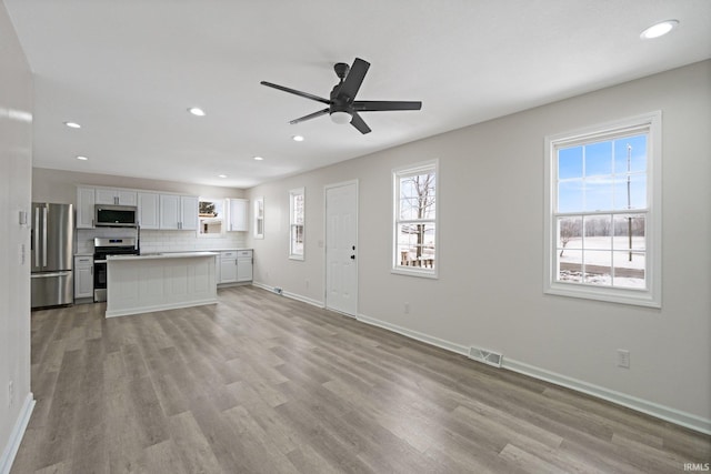 unfurnished living room with plenty of natural light, ceiling fan, and light wood-type flooring