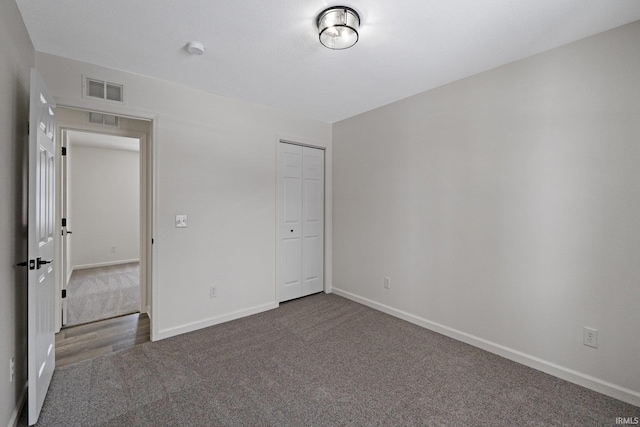 unfurnished bedroom with a closet and dark colored carpet