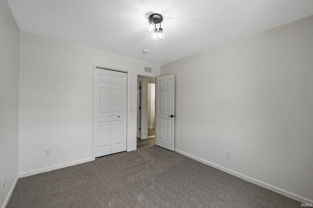 unfurnished bedroom with a closet and dark colored carpet