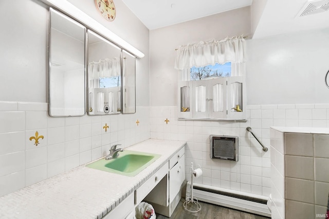 bathroom with vanity, a baseboard radiator, tile walls, and hardwood / wood-style flooring