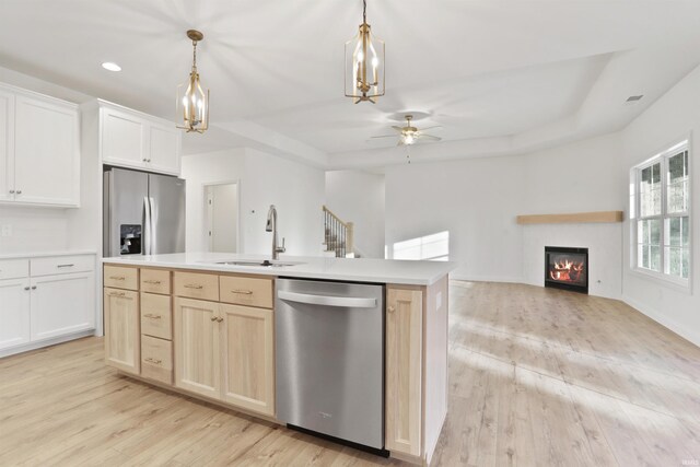 kitchen featuring a center island with sink, decorative light fixtures, light wood-type flooring, and stainless steel appliances