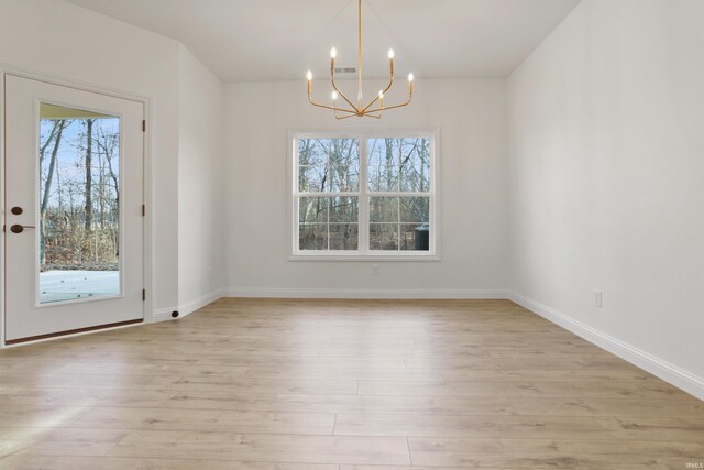 unfurnished dining area with light hardwood / wood-style floors and an inviting chandelier