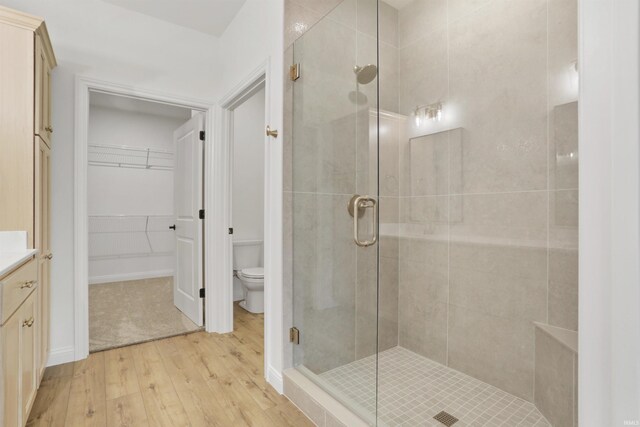 bathroom with hardwood / wood-style floors, vanity, toilet, and walk in shower