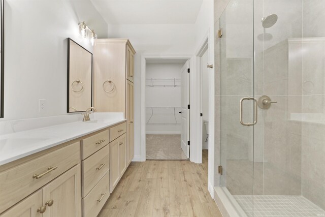 bathroom with wood-type flooring, vanity, toilet, and a shower with shower door