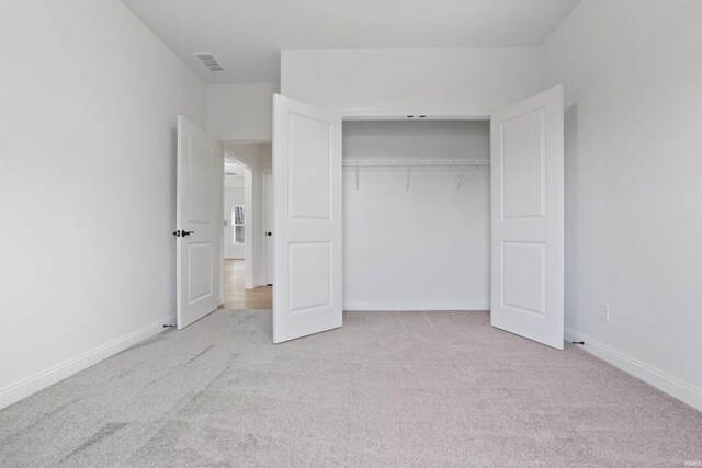 unfurnished bedroom featuring light carpet and a closet