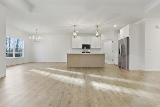 kitchen with white cabinets, light wood-type flooring, stainless steel appliances, and a large island