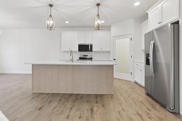 kitchen featuring white cabinetry, a center island with sink, hanging light fixtures, and appliances with stainless steel finishes