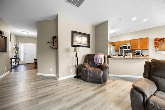 living room featuring light wood-type flooring and a textured ceiling