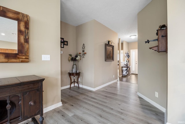 corridor with light hardwood / wood-style flooring and a textured ceiling