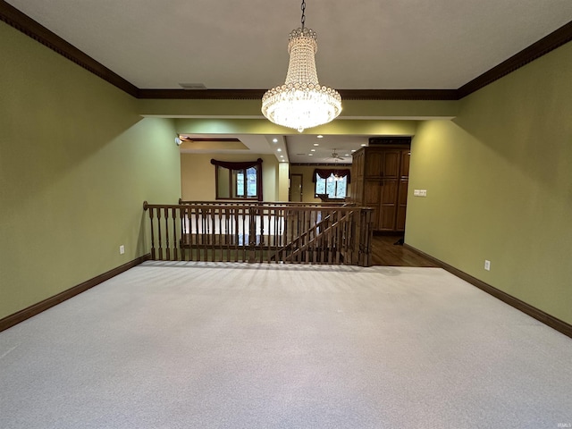 carpeted empty room featuring crown molding and a chandelier