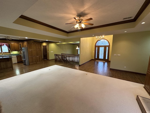 interior space with ornamental molding, a textured ceiling, ceiling fan with notable chandelier, a tray ceiling, and dark hardwood / wood-style floors