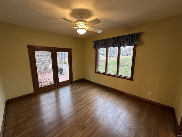 spare room featuring a textured ceiling, plenty of natural light, ceiling fan, and dark hardwood / wood-style floors