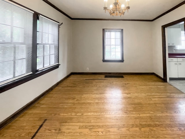 unfurnished room featuring crown molding, light hardwood / wood-style flooring, and a chandelier