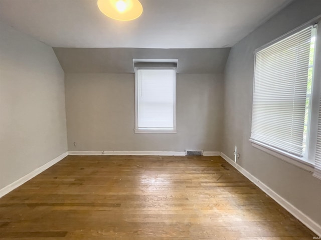 unfurnished room featuring wood-type flooring and vaulted ceiling