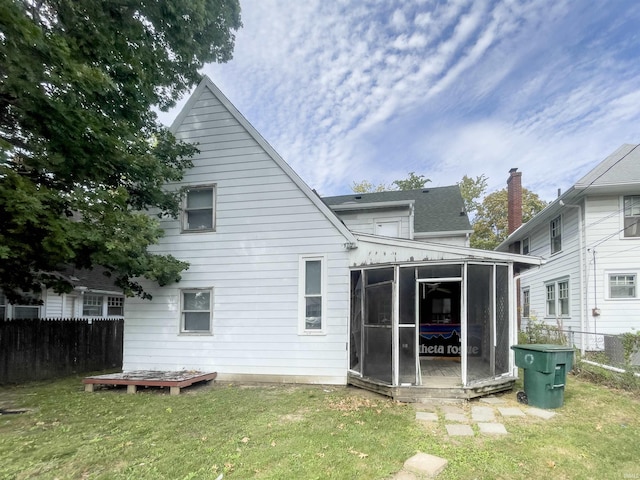 rear view of house with a sunroom and a lawn