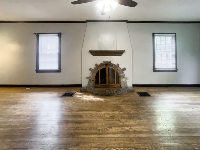 unfurnished living room featuring ceiling fan, crown molding, wood-type flooring, and a fireplace