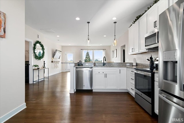 kitchen with kitchen peninsula, appliances with stainless steel finishes, sink, decorative light fixtures, and white cabinetry