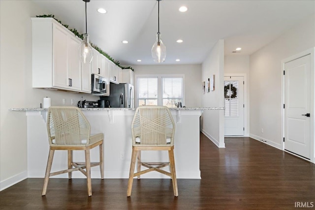 kitchen featuring kitchen peninsula, white cabinetry, hanging light fixtures, and stainless steel appliances