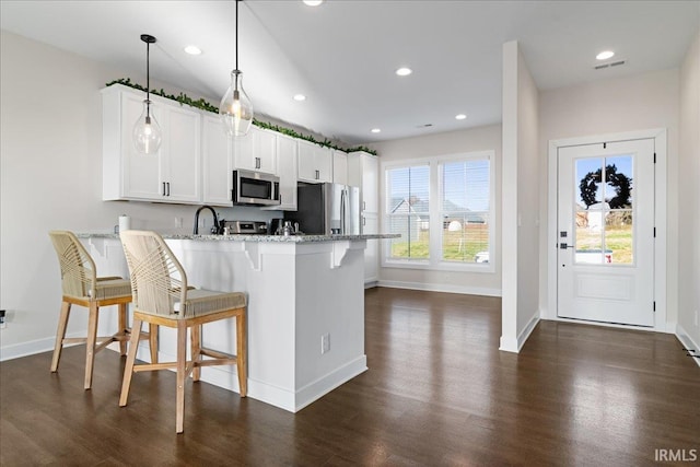 kitchen featuring white cabinets, a breakfast bar, kitchen peninsula, and stainless steel appliances