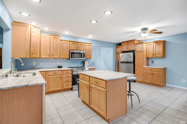 kitchen with ceiling fan, sink, stainless steel appliances, a kitchen bar, and light tile patterned floors