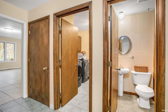 interior space featuring a textured ceiling, sink, tile patterned flooring, independent washer and dryer, and toilet