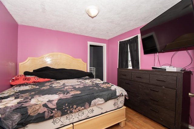 bedroom with light hardwood / wood-style flooring and a textured ceiling