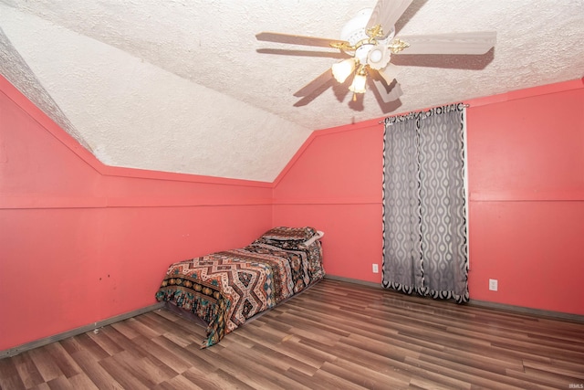 bedroom with a textured ceiling, ceiling fan, dark hardwood / wood-style floors, and vaulted ceiling