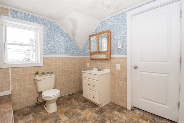 bathroom with vanity, toilet, and tile walls