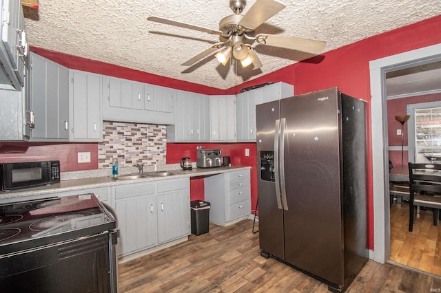 kitchen with stainless steel fridge, range with electric stovetop, dark wood-type flooring, and sink